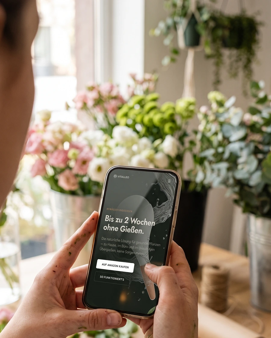 Eine Hand hält ein Telefon mit einer von uns gebauten Website, im Hintergrund ein Blumenladen